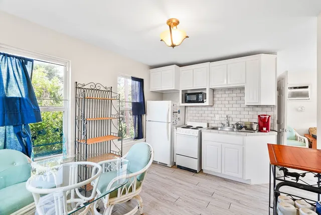 a kitchen with stainless steel appliances kitchen island granite countertop a stove a refrigerator a sink dishwasher and white cabinets with wooden floor