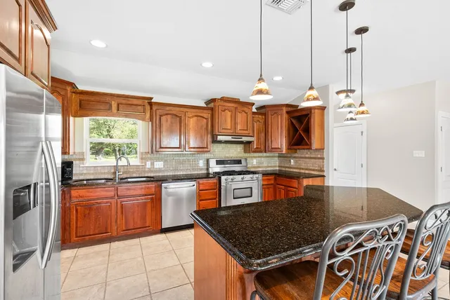 a kitchen with stainless steel appliances granite countertop a stove a sink and a granite counter tops with white cabinets