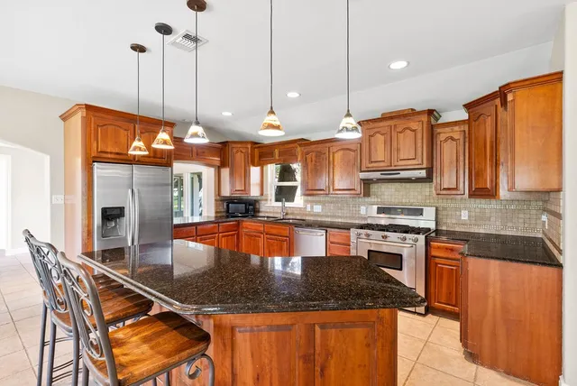 a kitchen with stainless steel appliances granite countertop a sink a stove and a wooden floors