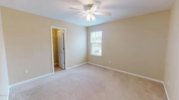 an empty room with windows and fan