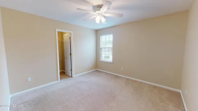 an empty room with windows and fan