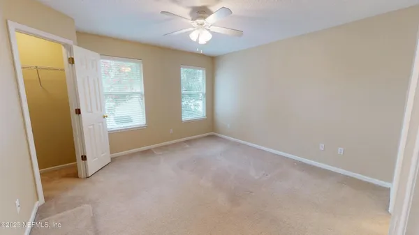 an empty room with windows and fan