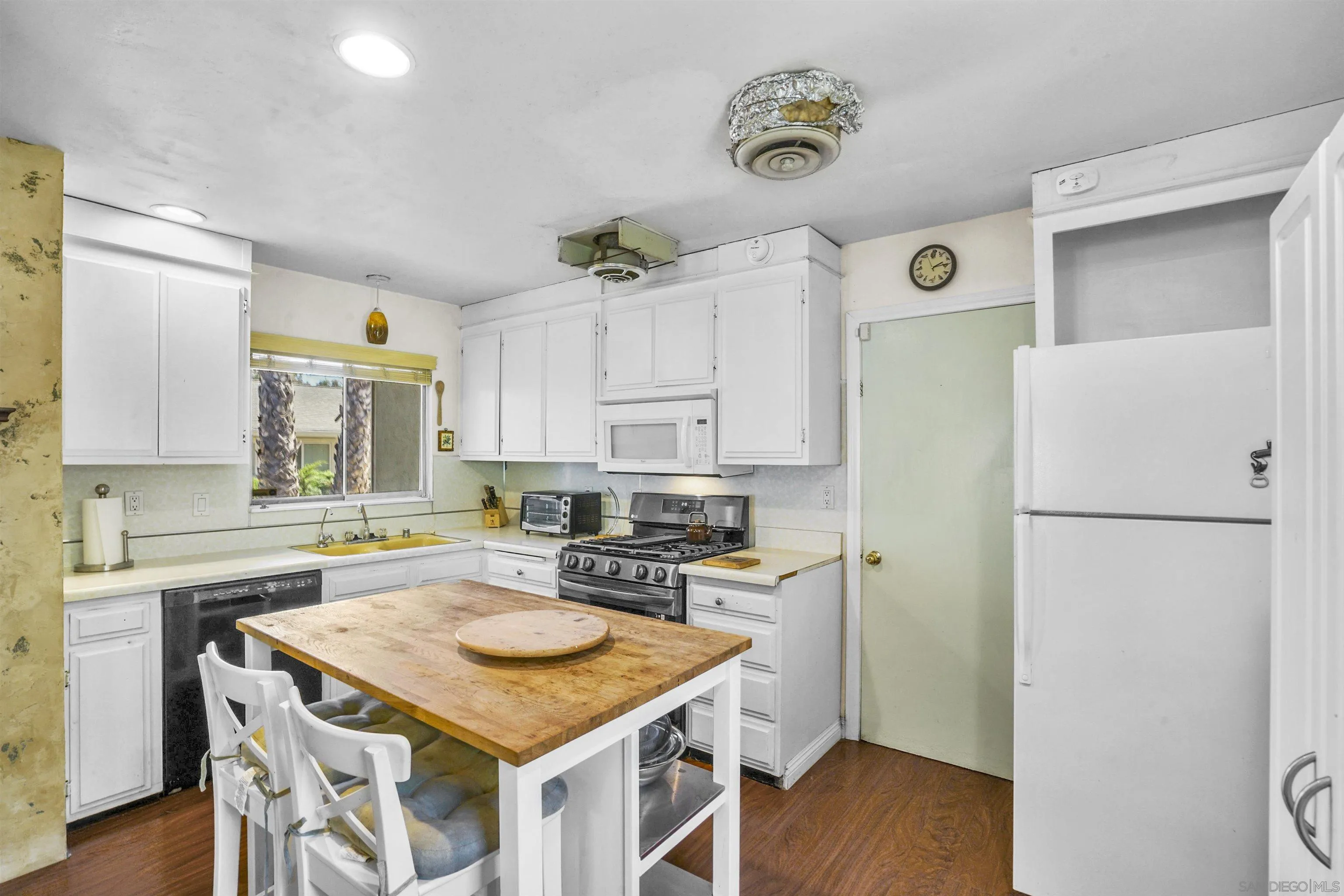 5785 Jackson Drive La Mesa, CA 91942 - Photo 3 of 20 a kitchen with a refrigerator a stove a sink and a dining table with wooden floor