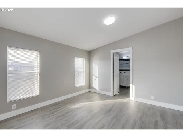 a view of an empty room with window and wooden floor