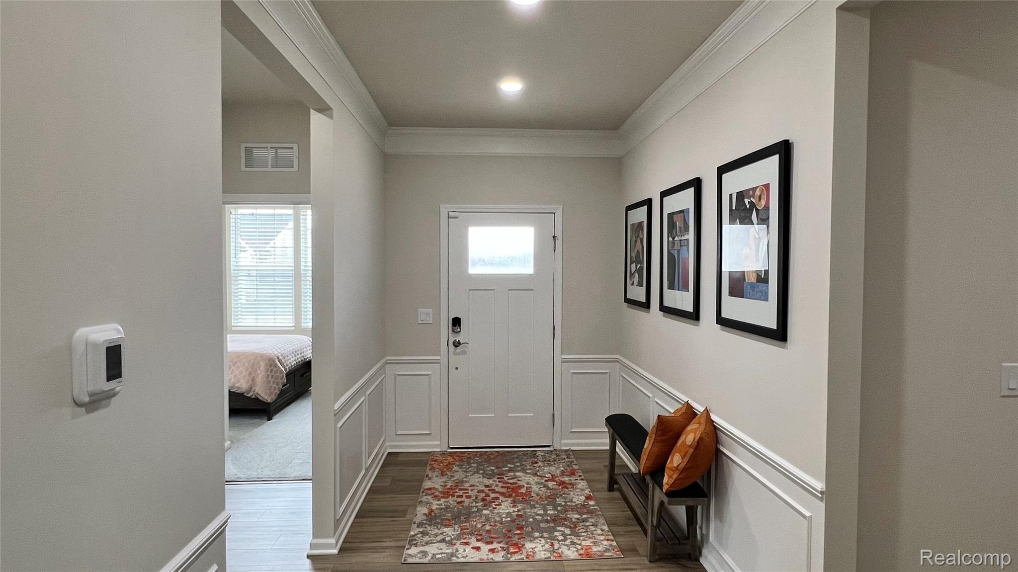 50192 Ogden Road Canton, MI 48188 - Photo 6 of 28 Foyer entrance featuring crown molding, dark wood-style floors, a decorative wall, and a wainscoted wall