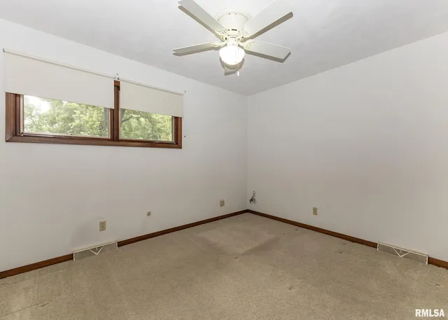 an empty room with a window and a ceiling fan