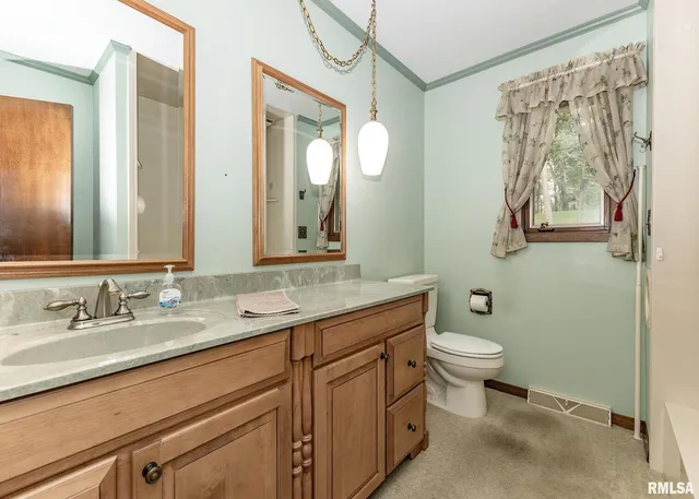 a bathroom with a granite countertop sink toilet and a mirror