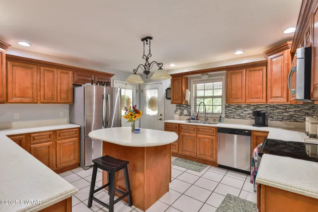 a kitchen with stainless steel appliances granite countertop a sink a stove a dining table and chairs