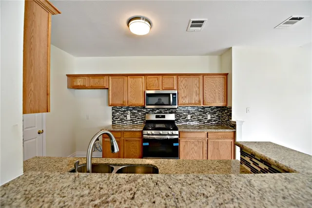 a kitchen with stainless steel appliances granite countertop a stove a sink and a microwave