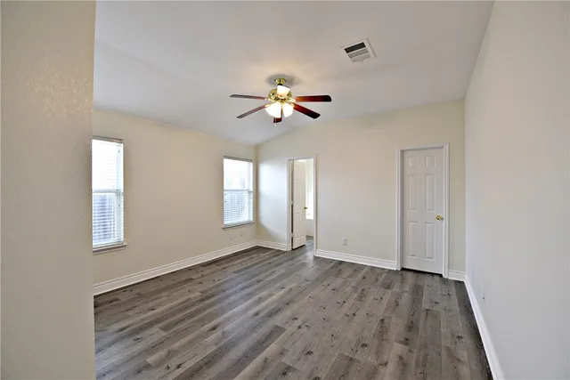 a view of an empty room with a window and wooden floor