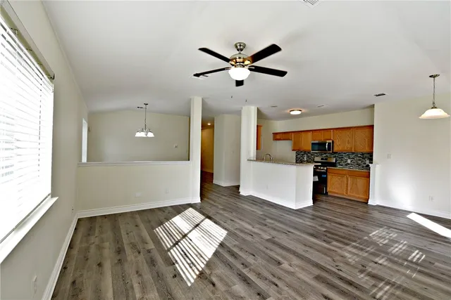 a view of empty room with wooden floor and window
