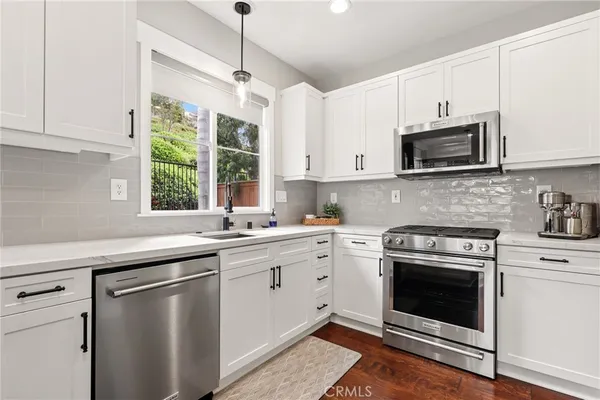 a kitchen with cabinets stainless steel appliances a sink and a window