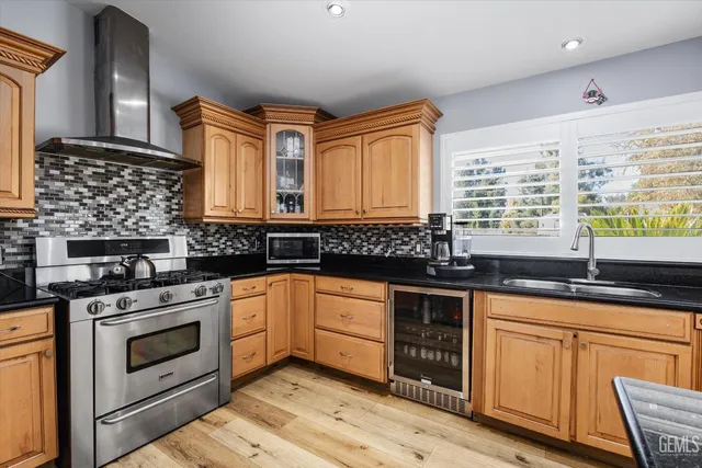 a kitchen with granite countertop a sink stainless steel appliances wooden floor and a window