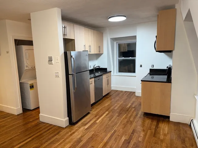 a view of a refrigerator in kitchen and an empty room
