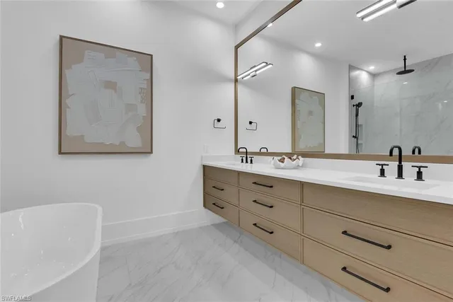 a bathroom with a double vanity sink mirror and bathtub
