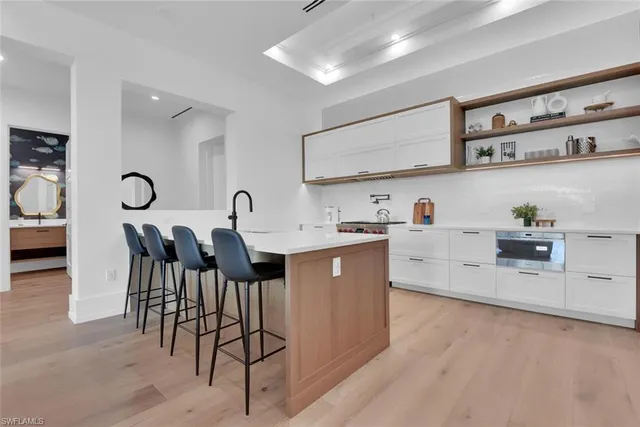 a kitchen with stainless steel appliances granite countertop a stove a sink a refrigerator and white cabinets with wooden floor