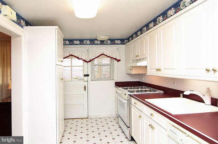 1227 Newfield Road Baltimore, MD 21207 - Photo 6 of 16 a kitchen with a refrigerator a sink and cabinets