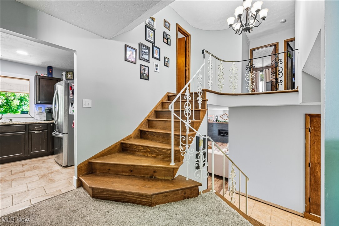 8193 Hartman Road Wadsworth, OH 44281 - Photo 4 of 50 Staircase featuring tile patterned floors, a chandelier, and carpet