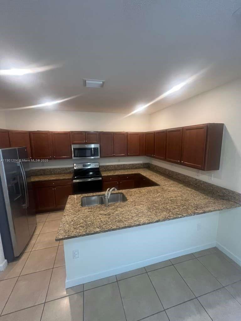 11481 Southwest 250th Street, Unit 11481 Homestead, FL 33032 - Photo 3 of 12 a kitchen with a stove and a sink