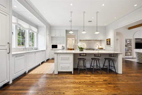 a large white kitchen with lots of counter space dining table and stainless steel appliances