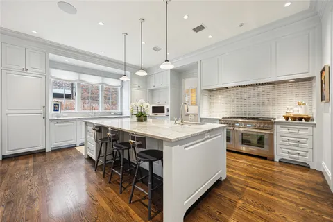 a kitchen with a stove a window and chairs