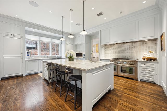 a kitchen with a stove a window and chairs