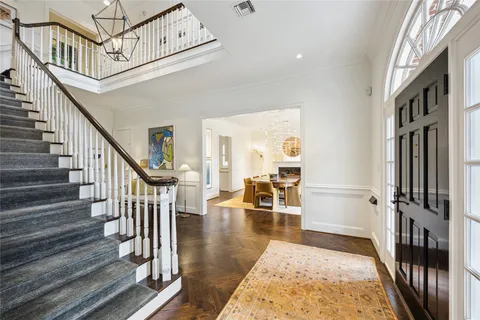a view of staircase with lots of frames on wall and a dining table next to a window