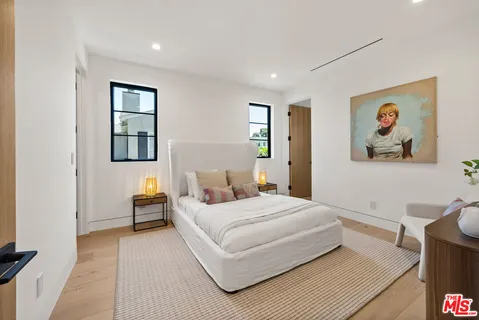 a bedroom with a bed wall painting and a window