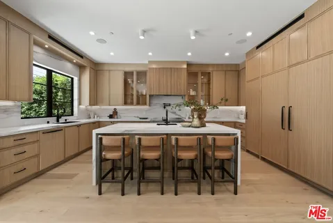 a kitchen with stainless steel appliances granite countertop a table chairs sink refrigerator and cabinets