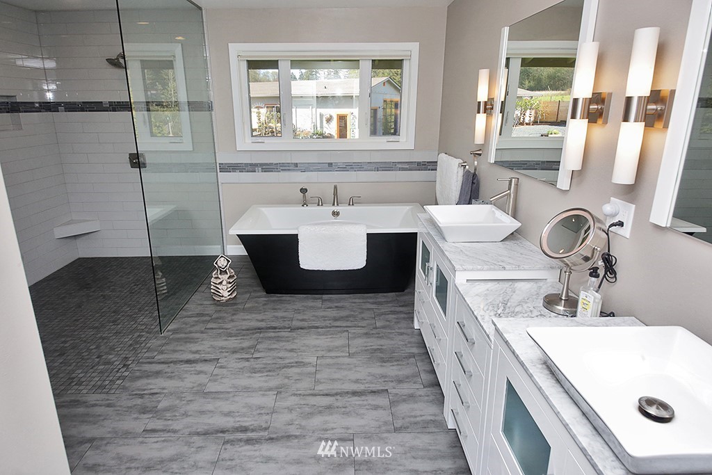1835 Lancaster Road Freeland, WA 98249 - Photo 17 of 25 a bathroom with a double vanity sink a mirror and a bathtub