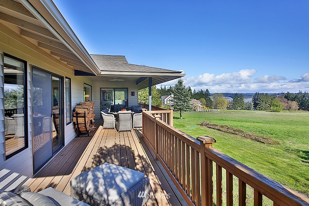 1835 Lancaster Road Freeland, WA 98249 - Photo 8 of 25 a view of a patio with dining table and chairs under an umbrella with large trees