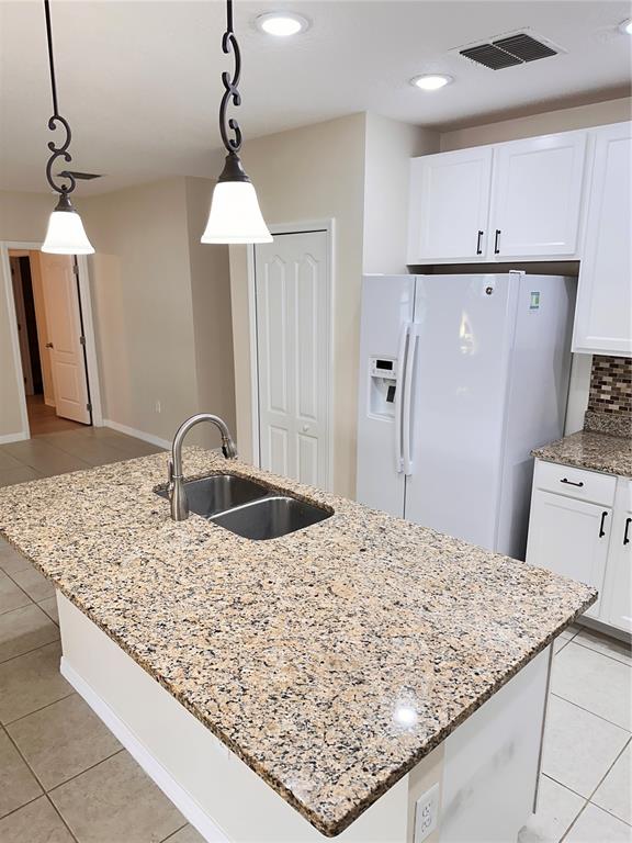 447 Pinecrest Loop Davenport, FL 33837 - Photo 10 of 23 a kitchen with kitchen island granite countertop a sink refrigerator and cabinets