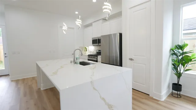 a kitchen with stainless steel appliances a microwave a sink a refrigerator and wooden floor