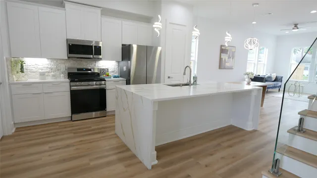 a kitchen with stainless steel appliances granite countertop a refrigerator a stove a sink and a microwave