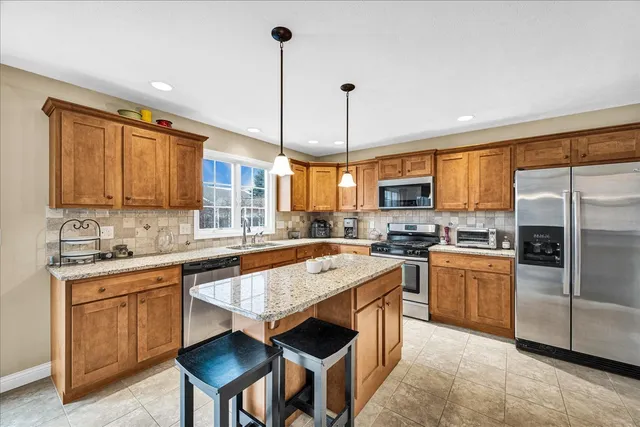a kitchen with stainless steel appliances granite countertop a stove a sink dishwasher a refrigerator and a wooden cabinets