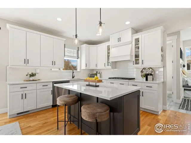 a kitchen with a sink a stove a refrigerator and white cabinets with wooden floor