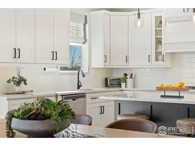 a kitchen with stainless steel appliances kitchen island granite countertop a sink a stove white cabinets and a granite counter tops