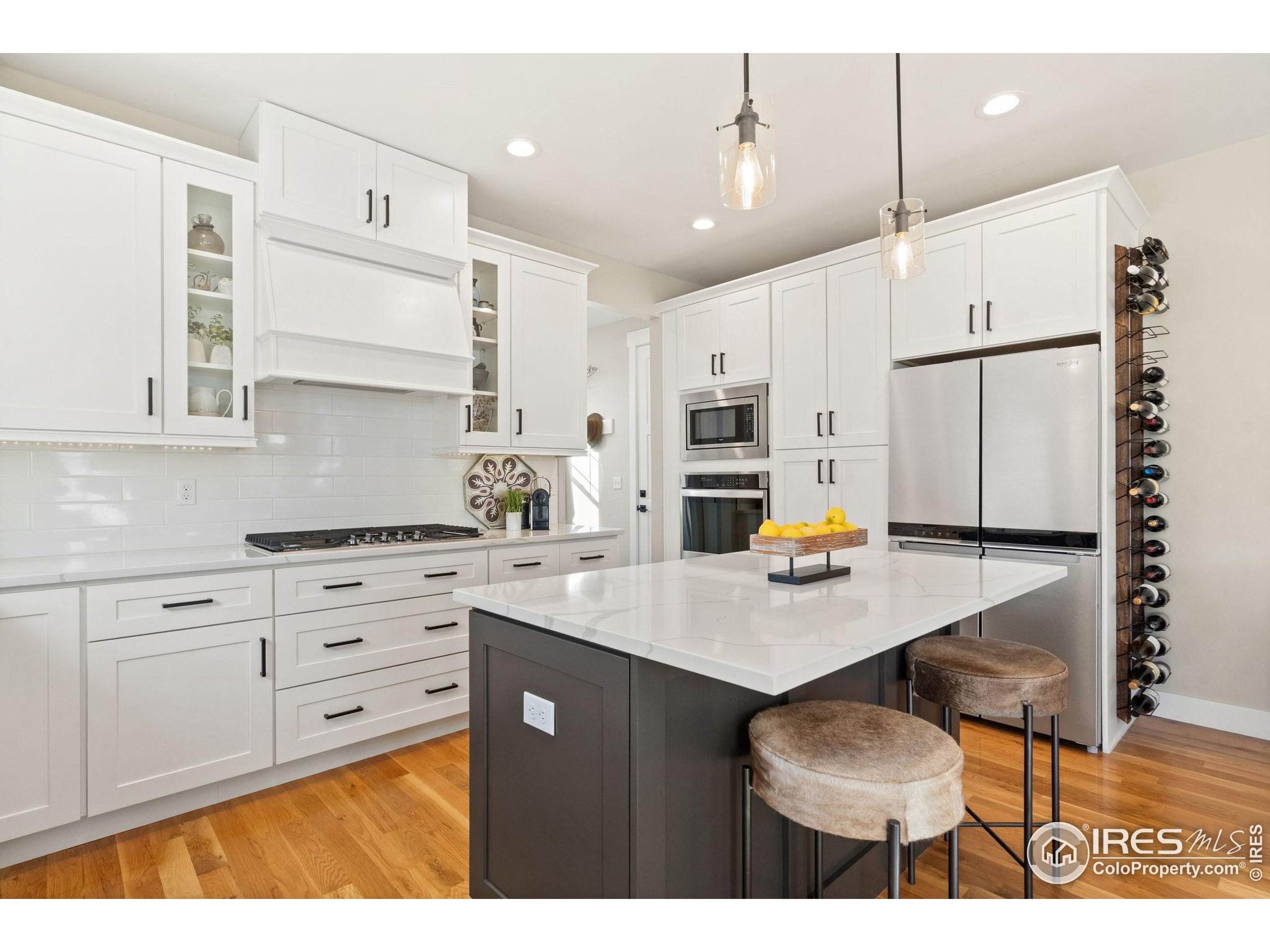 2032 Cuda Court Berthoud, CO 80513 - Photo 14 of 38 a kitchen with stainless steel appliances kitchen island granite countertop a stove a sink dishwasher and white cabinets with wooden floor