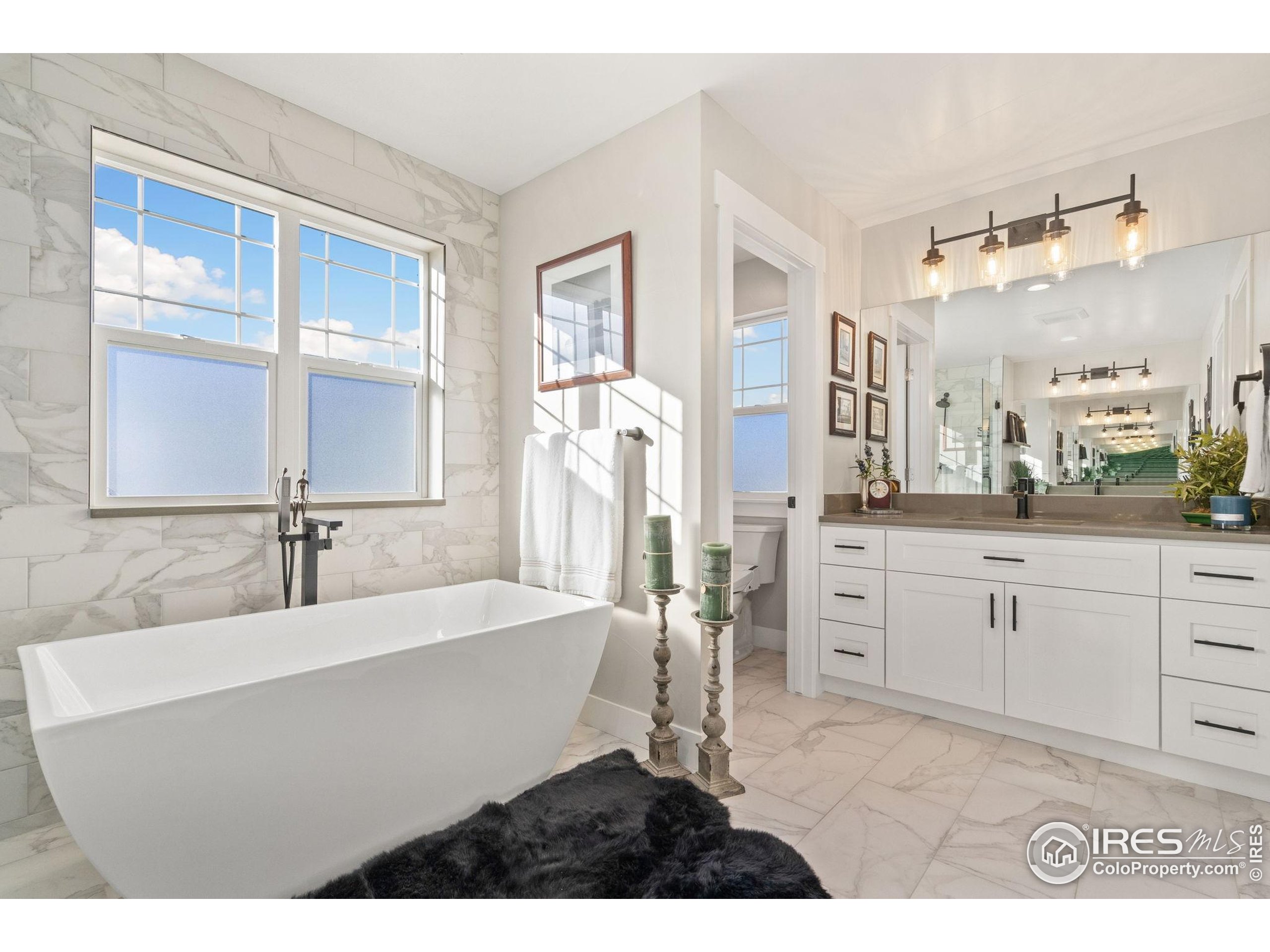 2032 Cuda Court Berthoud, CO 80513 - Photo 24 of 38 a bathroom with a sink tub double vanity and mirror