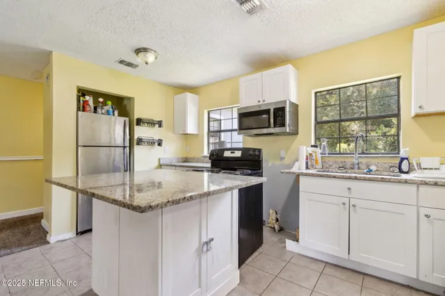 a kitchen with stainless steel appliances granite countertop a sink stove refrigerator and microwave