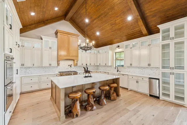 a large white kitchen with cabinets a sink and stainless steel appliances
