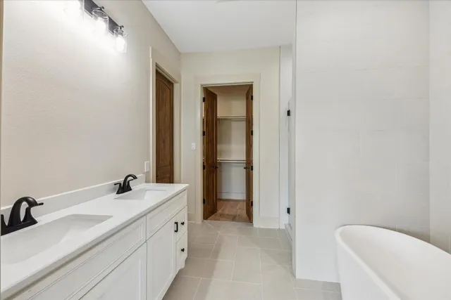 a bathroom with a double vanity sink a mirror and a bathtub