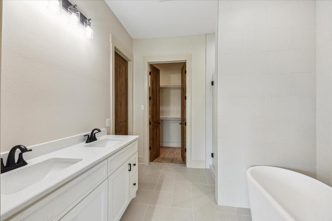2130 Hartfield Road Round Top, TX 78954 - Photo 24 of 39 a bathroom with a double vanity sink a mirror and a bathtub