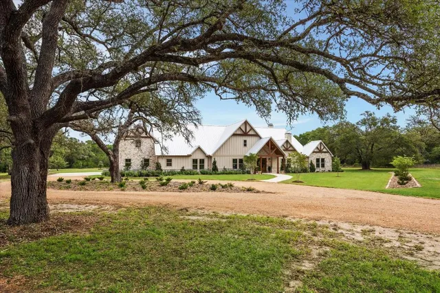 a front view of a house with a yard and large trees