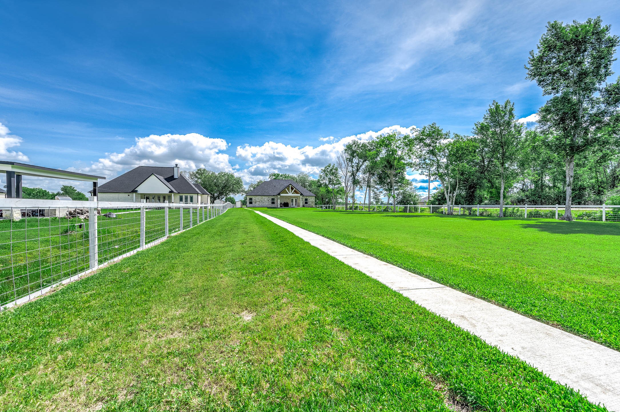 8032 Short Road Needville, TX 77461 - Photo 40 of 50 The expansive green space and scenic surroundings create a peaceful outdoor setting with plenty of room to enjoy the property’s acreage. Surrounded by mature trees and fenced boundaries, the backyard offers both privacy and functionality