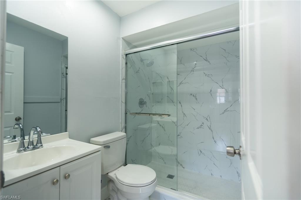 1940 48th Street Southwest Naples, FL 34116 - Photo 29 of 33 Bathroom with a glass-enclosed shower featuring marble-look wall panels and a sliding door