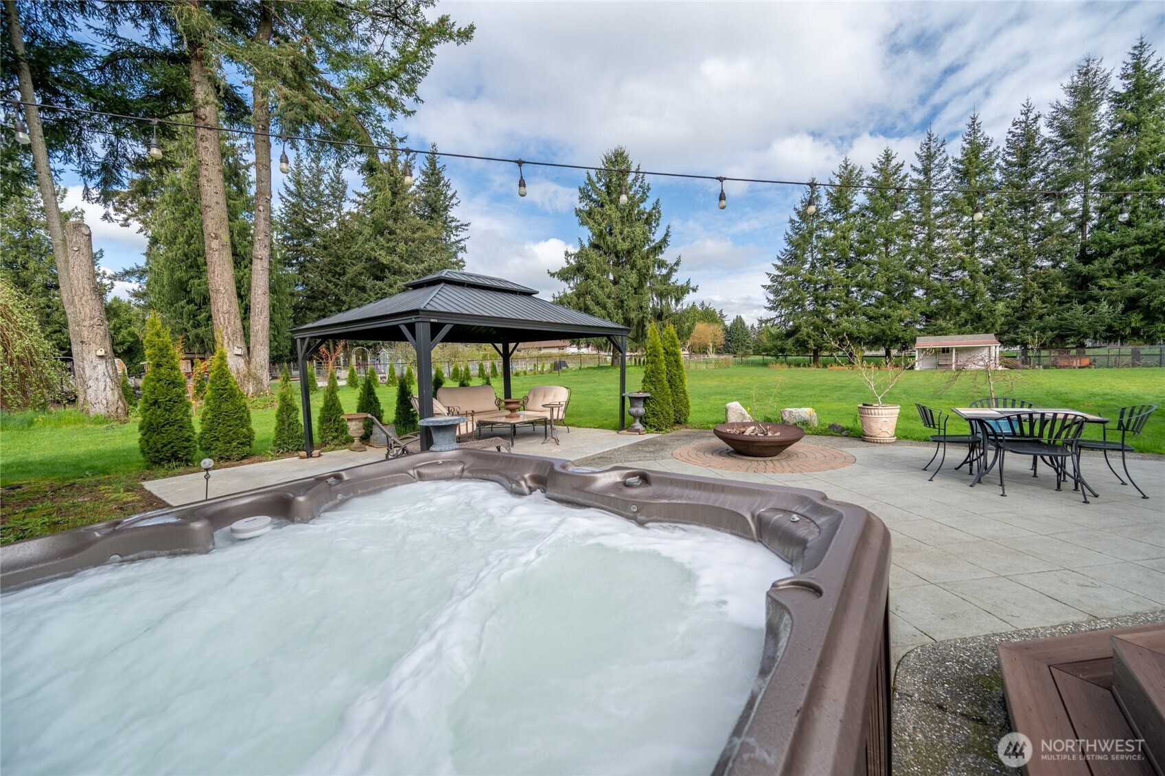770 East Wiser Lake Road Lynden, WA 98264 - Photo 25 of 36 a view of a patio with a table and chairs under an umbrella with large trees