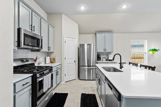 a kitchen with stainless steel appliances a stove sink microwave and refrigerator