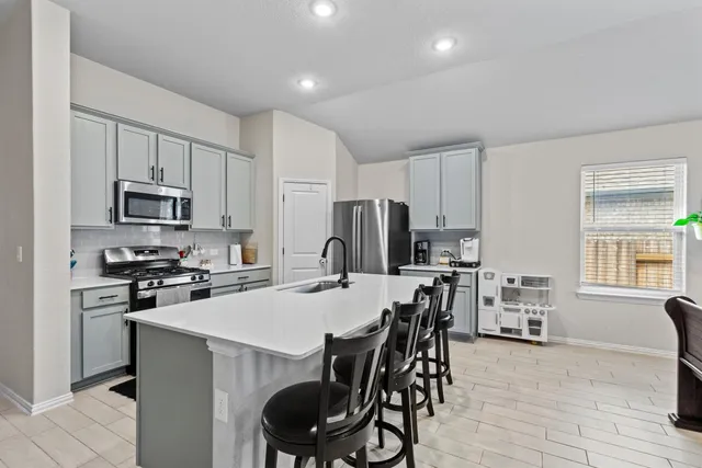 a kitchen with stainless steel appliances a table chairs microwave and refrigerator
