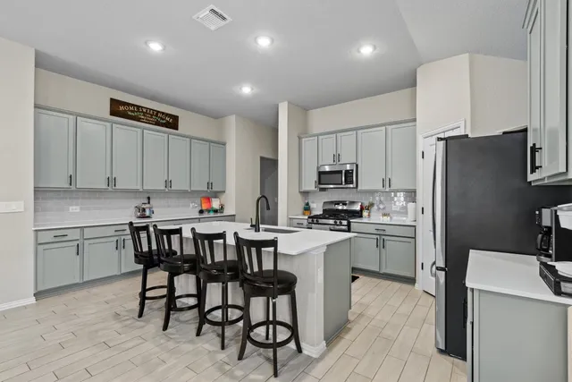 a kitchen that has a lot of cabinets a sink and appliances in it